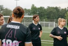 Jogadoras de futebol feminino conversam e analisam estratégias em um campo ao ar livre.