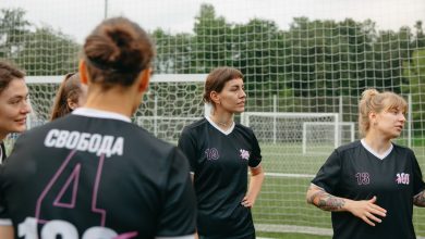 Jogadoras de futebol feminino conversam e analisam estratégias em um campo ao ar livre.