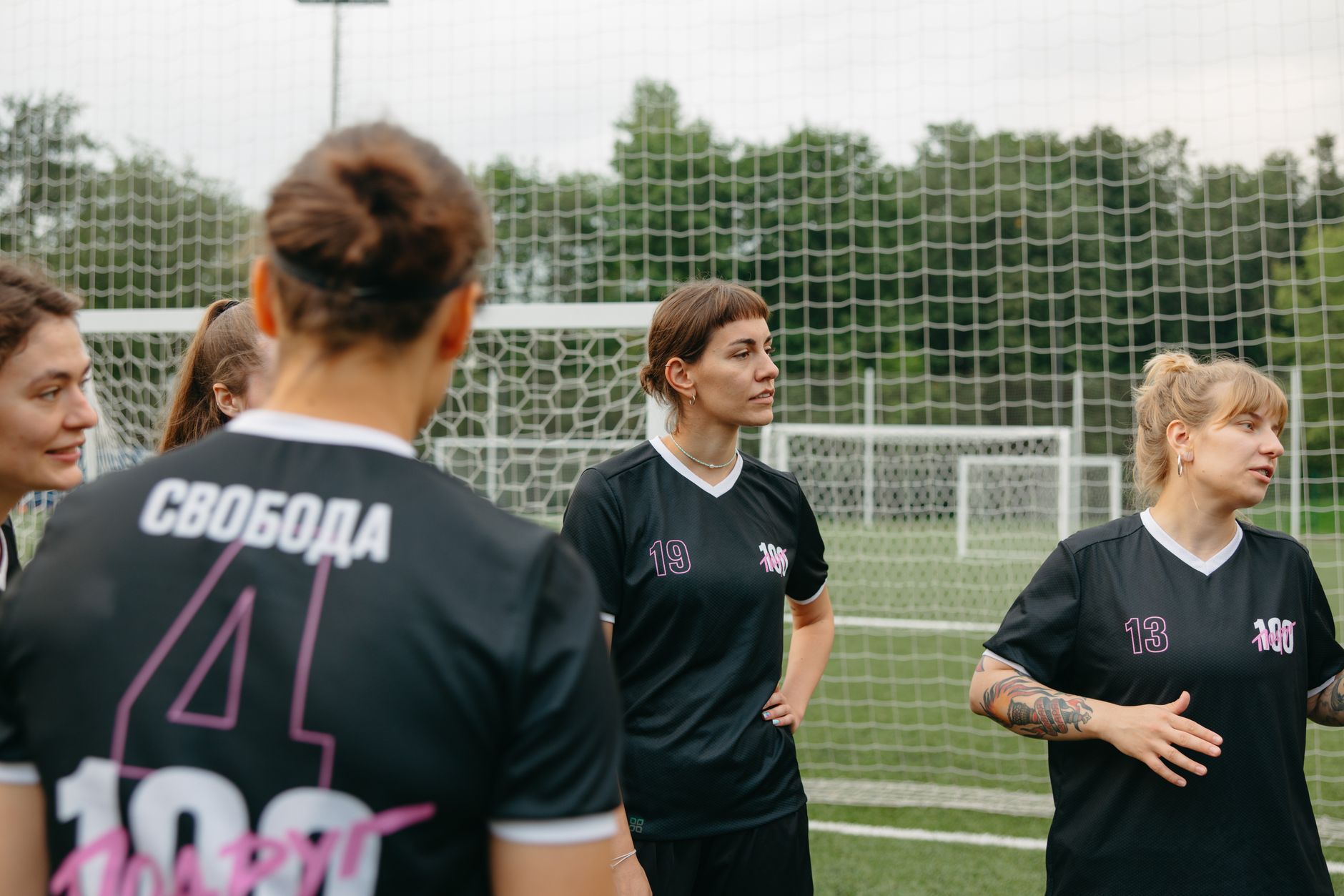 Jogadoras de futebol feminino conversam e analisam estratégias em um campo ao ar livre.