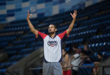 Árbitro sinaliza durante uma partida de basquete em um ginásio.