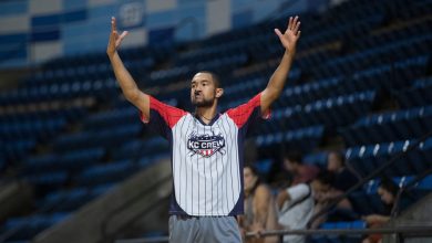Árbitro sinaliza durante uma partida de basquete em um ginásio.