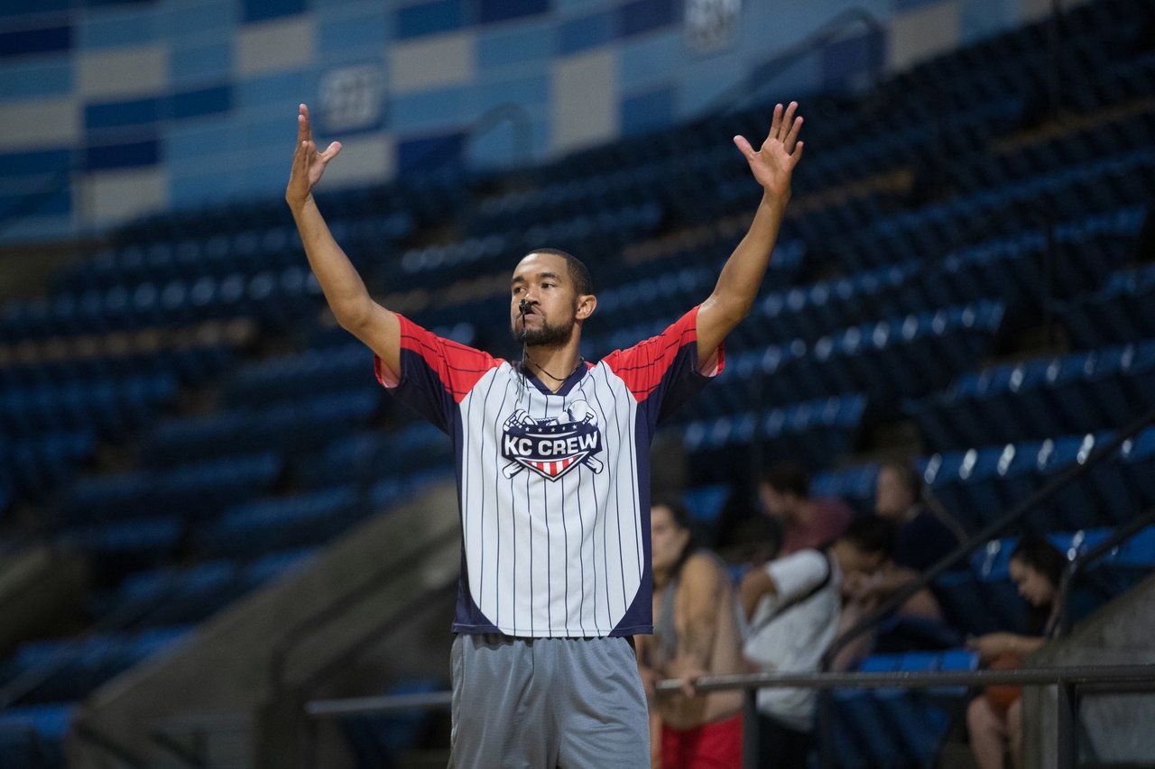 Árbitro sinaliza durante uma partida de basquete em um ginásio.