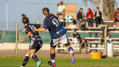 Duas jogadoras disputam a bola durante uma partida de futebol feminino ao ar livre.