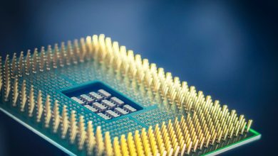 Close de um chip de processamento com pinos dourados sobre fundo azul.