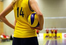 Jogadores disputam uma partida de vôlei em um ginásio lotado.